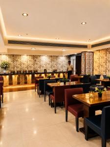 a restaurant with tables and chairs and a chef in the background at Hotel Cymbal -Sector 31 Gurgaon in Gurgaon
