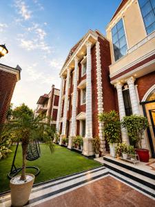 a large brick building with a green lawn at Hotel Cymbal -Sector 31 Gurgaon in Gurgaon