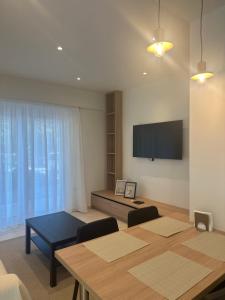 a living room with a table and a flat screen tv at Rodos Suites on the Park in Rhodes Town