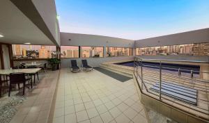a large room with a pool and a table and chairs at Plaza Inn Augustus - Downtown in Goiânia