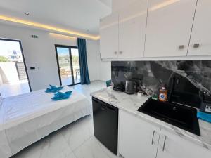 a kitchen with white cabinets and a bed in a room at Central Luxury Rooms in Alikanas