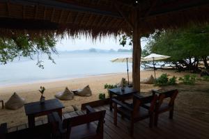 a beach with two tables and chairs and umbrellas at The Woods Beachfront Tent Yao Noi in Ko Yao Noi