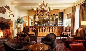 a living room with a fireplace and a bar at Fawsley Hall Hotel in Daventry