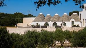 a building with a roof with trees in the foreground at Masseria Calandrella in Noci