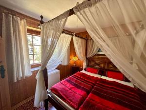 a bedroom with a canopy bed with red sheets and a window at In Benz da brennt's in Benz