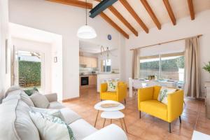 a living room with a white couch and yellow chairs at Villa Aries by 3VILLAS in Cala en Forcat