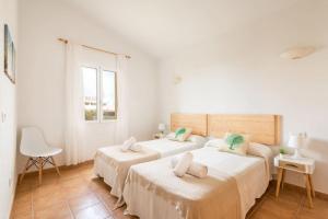 two beds in a room with white walls at Villa Aries by 3VILLAS in Cala en Forcat +52 photos