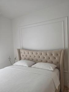 a white bedroom with a large bed with white sheets at Stan na dan Podgorica Mne in Podgorica