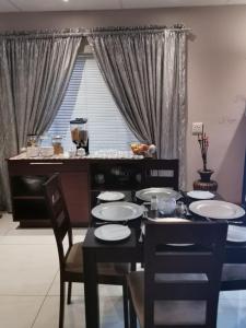 a dining room with a table and chairs and a window at Feathers Guest House in Welkom