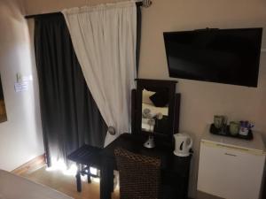 a room with a table and a television on the wall at Feathers Guest House in Welkom