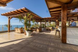 a man sitting at a bar on a patio overlooking the ocean at Pestana Carlton Madeira Ocean Resort Hotel in Funchal