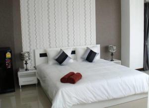 a white bed with two red towels on it at Grand Residence Jomtien in Jomtien Beach