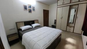 a bedroom with a large bed with white sheets at BMK Inn in Bangalore +3 photos