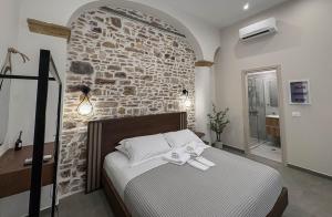 a bedroom with a stone wall and a bed at Ralli 34 ROOMS&APTS in Chios