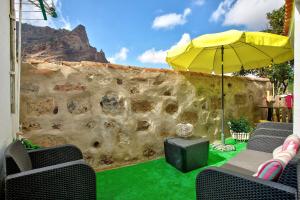 a patio with a stone wall and an umbrella at Casa del Callejon in Tejeda
