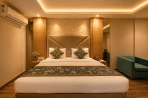 a bedroom with a large bed and a green chair at The Waves Hotel with Free Airport Pickup or Drop in New Delhi