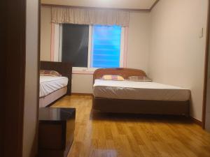 two beds in a small room with a window at Sorak Garden Resortel in Sokcho