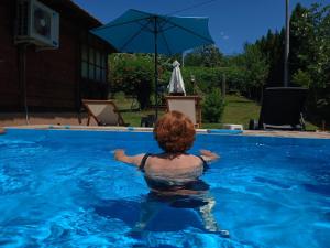 a woman in a swimming pool with an umbrella at Etno domacinstvo Stankovic apartman br 2 in Gornji Milanovac