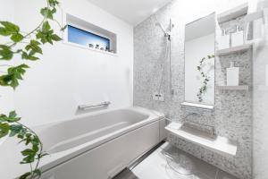 a white bathroom with a tub and a sink at The Prestige in Asahikawa