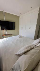 a bedroom with a large white bed with a flat screen tv at The Manor in Manzini