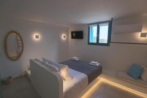 a white room with a bed and a mirror at Liotrivi Luxury Residences in Kithnos +89 photos