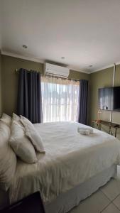 a bedroom with a large white bed with a window at The Manor in Manzini