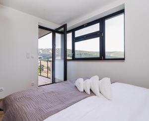 a bedroom with a white bed with large windows at Enzian by Mountain ways in Loučná pod Klínovcem
