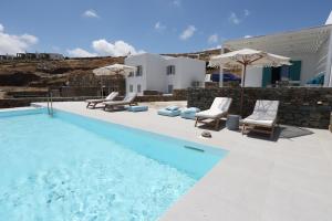 a pool with chairs and umbrellas next to a building at Liotrivi Luxury Residences in Kithnos