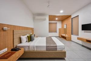 a bedroom with a large bed and a television at Hotel Fountain - Kamrej in Surat