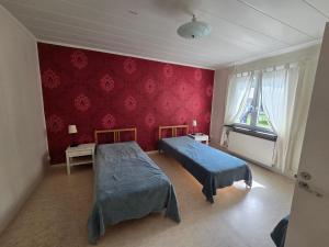a bedroom with two beds and a red wall at Ljusnefors Camping in Ljusne