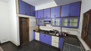 a kitchen with blue cabinets and a microwave at BMK Inn in Bangalore