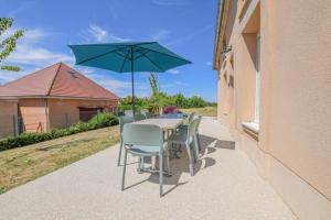 a table with chairs and an umbrella on a patio at Numéro 3 in Morvilliers