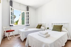two beds in a room with two windows at Casa Carlos - Villa en Son Cabrises in Cala Blanca +25 photos
