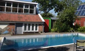a swimming pool in front of a house with solar panels at Countryside Eco Natuurhuisjes in Ee