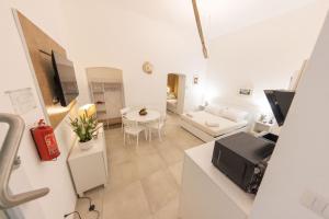 a white living room with a white couch and a tv at Luma Apartment Sperlonga in Sperlonga