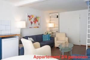 a living room with a blue couch and white chairs at opdehoekvandestal in Workum