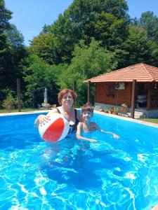 a woman and a child in a swimming pool with a beach ball at Etno Domaćinstvo Stanković in Gornji Milanovac