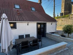a patio with a table and chairs and a building at Le Fournil in Fiennes
