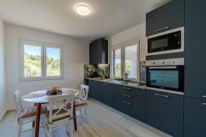 a kitchen with dark blue cabinets and a table with a table at Mediterranean vacation home in Blato