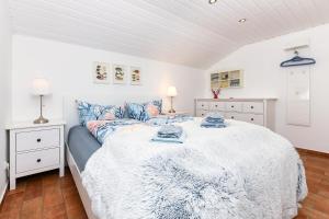a white bedroom with a large bed with blue pillows at Ferienhaus Sternenklar in Wittmund