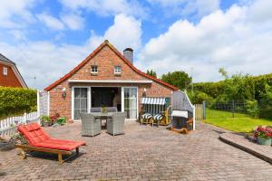 a brick house with a patio with chairs and a grill at Ferienhaus Sternenklar in Wittmund