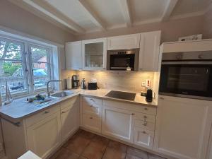 a kitchen with white cabinets and a sink and a microwave at Inseltraum in Wrixum