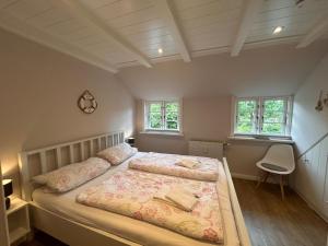 a bedroom with two beds and a chair and two windows at Inseltraum in Wrixum
