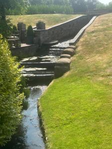 a river with a stone bridge in a field at Astwell Mill Private accommodation near Silverstone in Helmdon