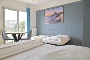 two beds in a room with a table and a window at MOTEL ASCOT - Hotel & Appartements in Cagnes-sur-Mer