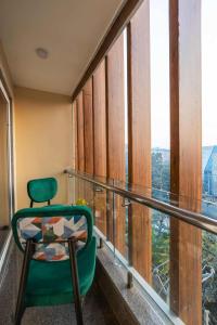 a green chair sitting on a balcony with a view at Saltstayz Select- Medicity Near Medanta Hospital in Gurgaon