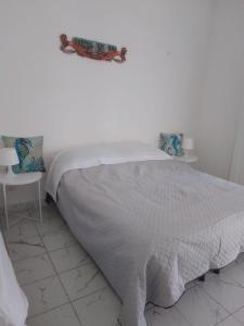 a white bed with a white blanket and two chairs at Ippocampo in Giardini Naxos