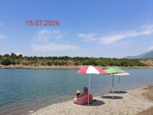 a person sitting on a beach under two umbrellas at SuperPanorama GuestHouse in Kukës +65 photos