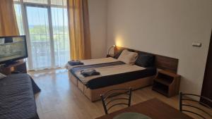 a hotel room with a bed and a television at Beach View Apartment Chernomorec in Chernomorets