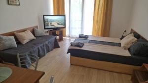 a room with a bed and a couch and a television at Beach View Apartment Chernomorec in Chernomorets +14 photos
